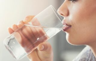 A woman is drinking a cup of tap water.