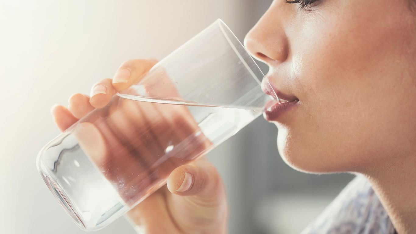 A woman is drinking a cup of tap water.
