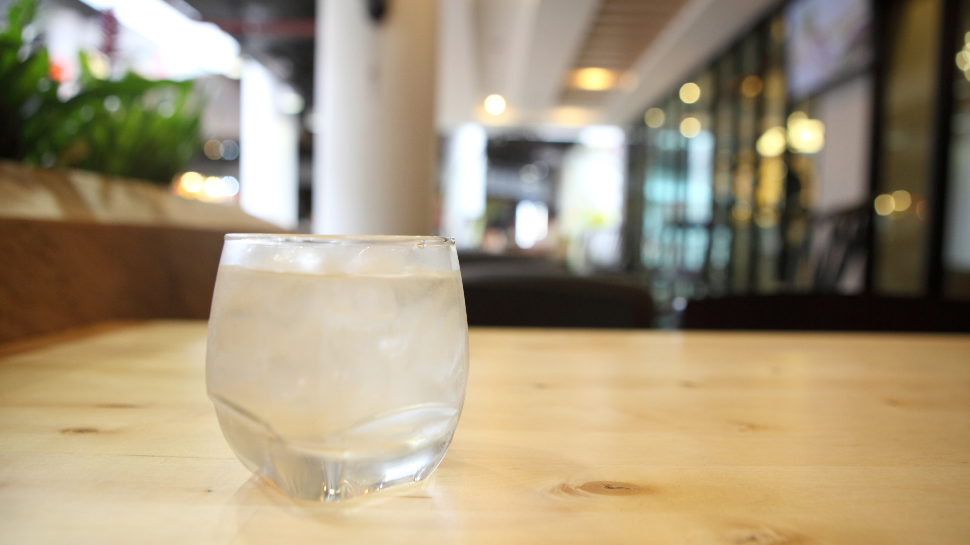 A filled glass of cold water on a table in a restaurant.