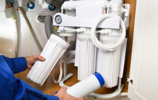 A technician changes the filter of a reserve osmosis system underneath a sink.