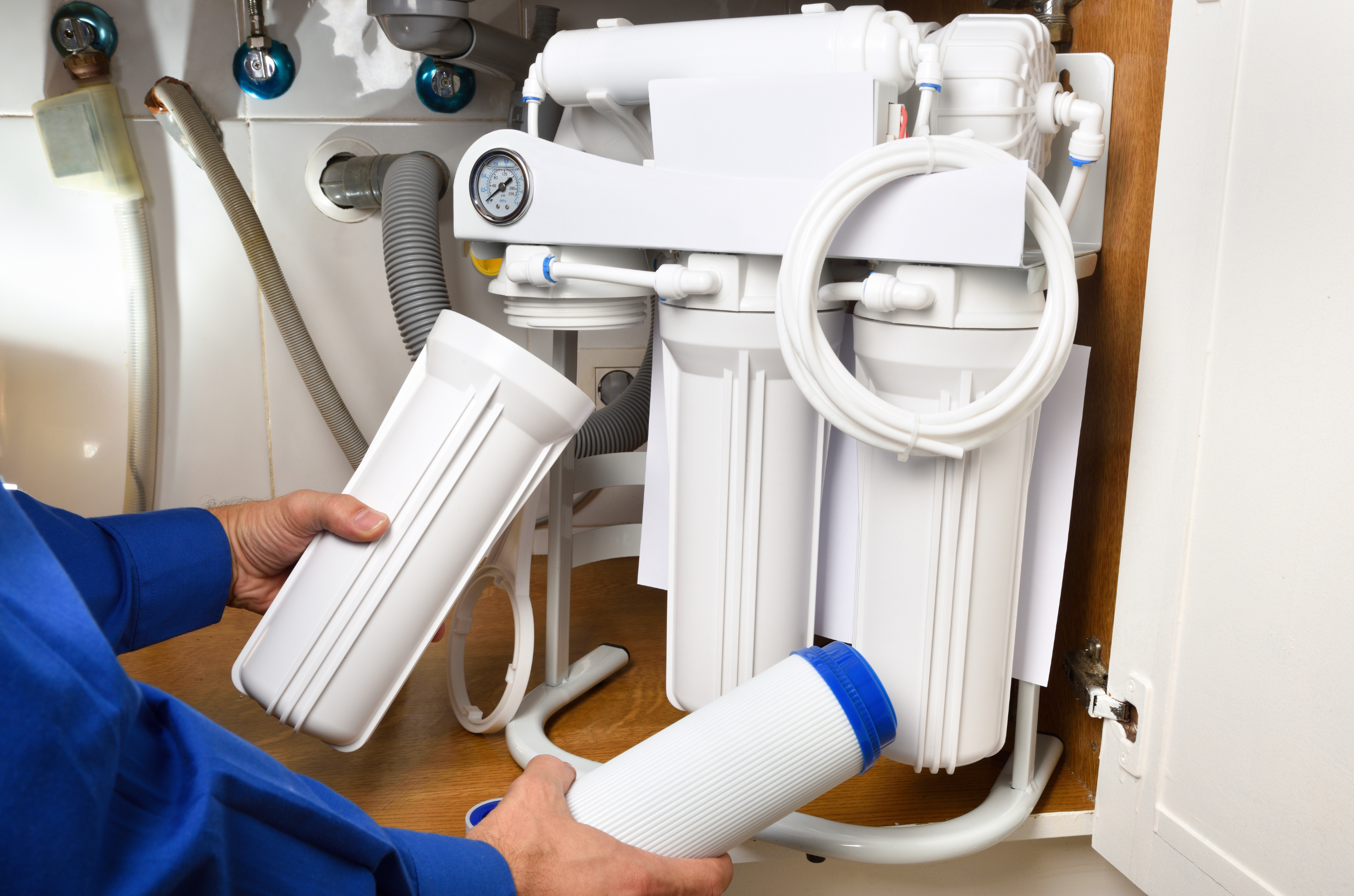 A technician changes the filter of a reserve osmosis system underneath a sink.